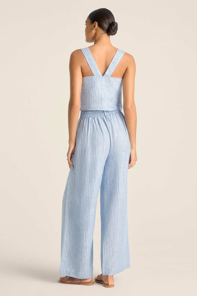 Woman faced away wearing a blue and white striped beach tank top with matching beach pants