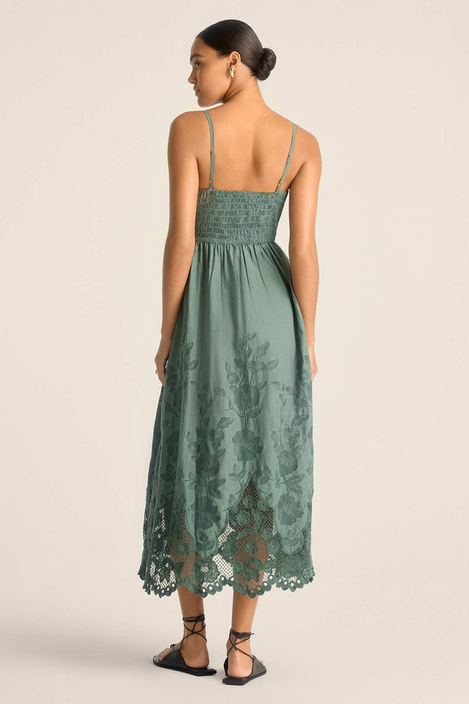 Woman faced away wearing a sea green lacy beach dress