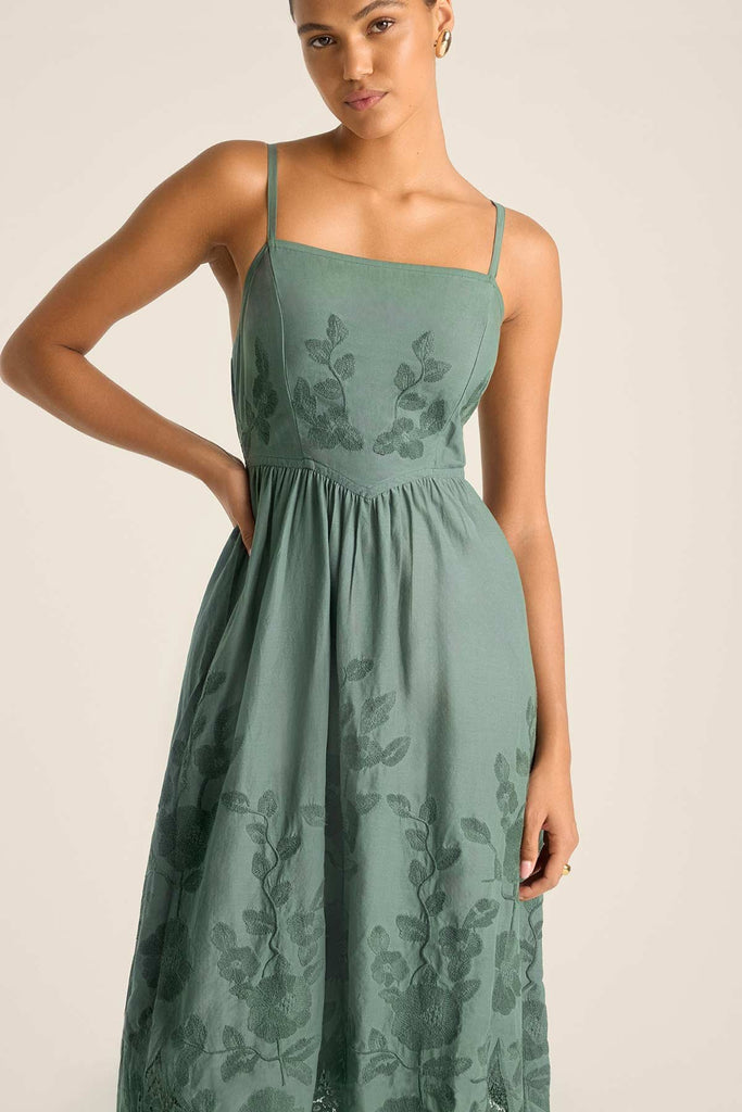 Woman wearing a sea green lacy beach dress with close up of detail
