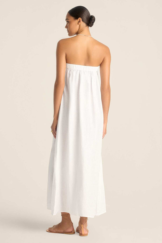 Woman turned away wearing a white bandeau style full length beach dress