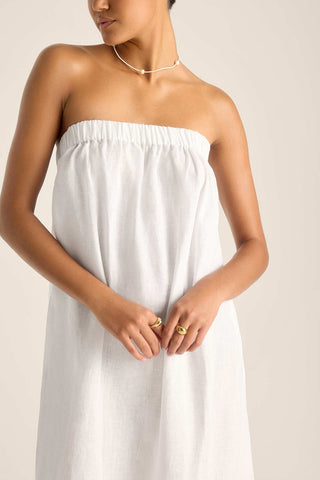 Woman wearing a white bandeau style beach dress with a close up of the detail