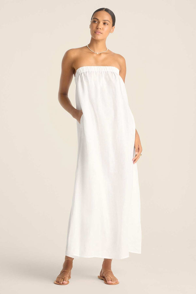 Woman wearing a white bandeau style full length beach dress
