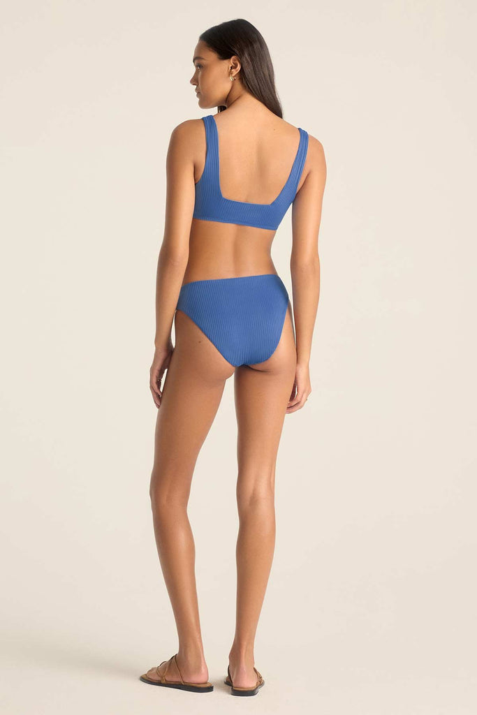 Woman turned away wearing a blue swim top with matching swim bottoms