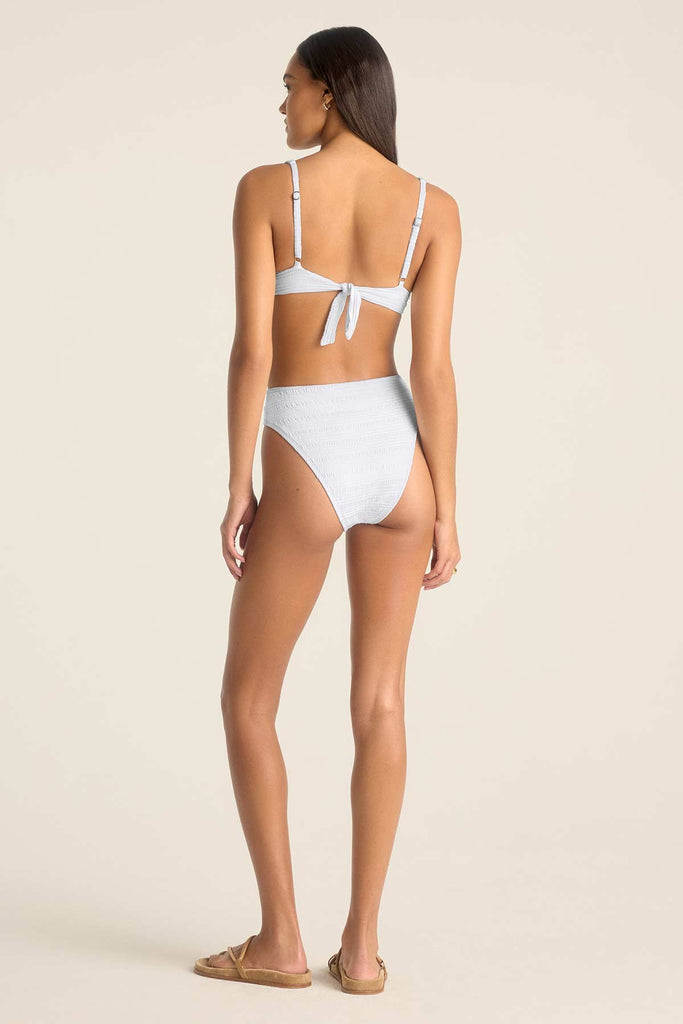 Woman faced away wearing a white bikini top with underwire and matching swim bottoms
