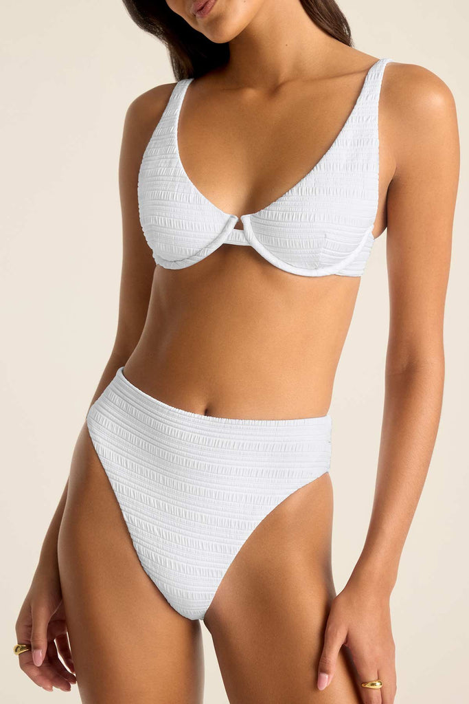 Woman wearing a white bikini top with underwire and matching swim bottoms. Close up for detail