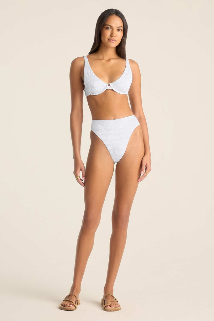 Woman wearing a white bikini top and matching high waisted white swim bottoms