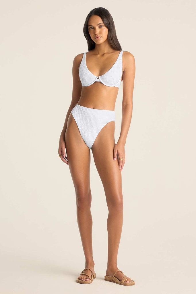 Woman wearing a white bikini top with underwire and matching swim bottoms