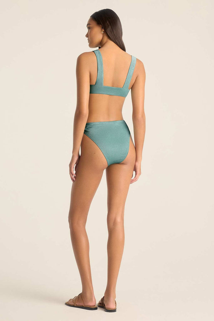 Woman turned away wearing a metallic aqua bikini top with matching swim bottoms