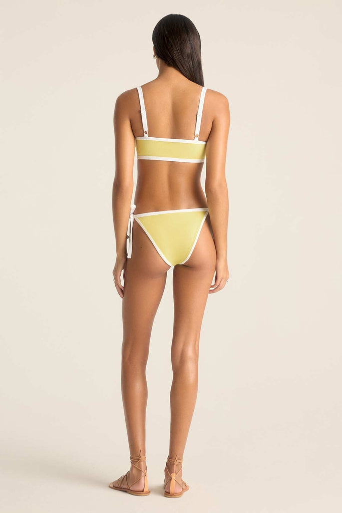 Woman turned away wearing a yellow bandeau swim top and matching swim bottoms with white trim