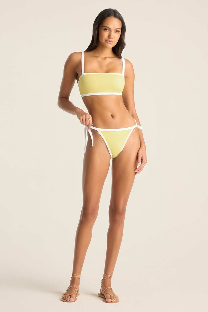 Woman wearing a yellow bandeau swim top and matching swim bottoms with white trim