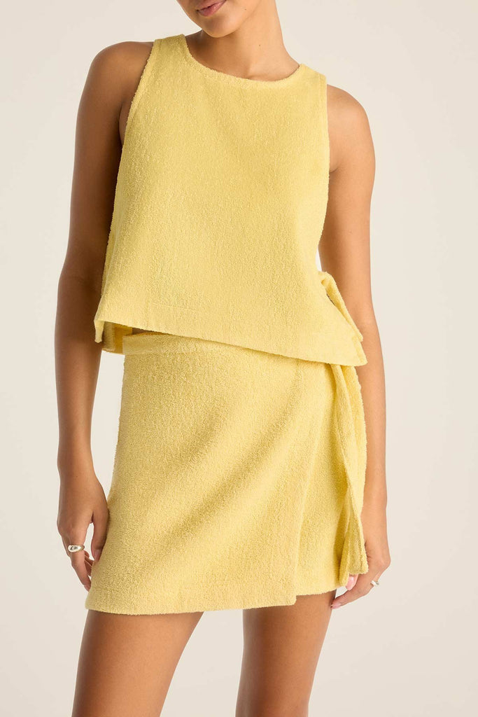 Woman wearing a yellow terry cloth tank top with a matching wrap skirt and close up of detail