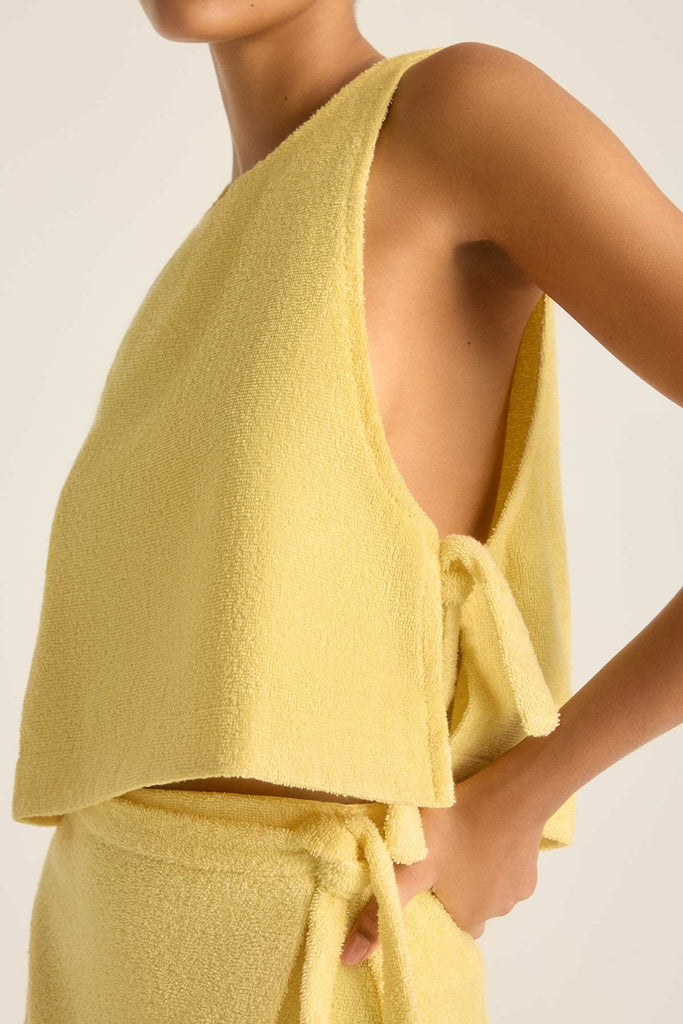 Woman wearing a yellow terry cloth tank top with a matching wrap skirt with a close up of the side detail