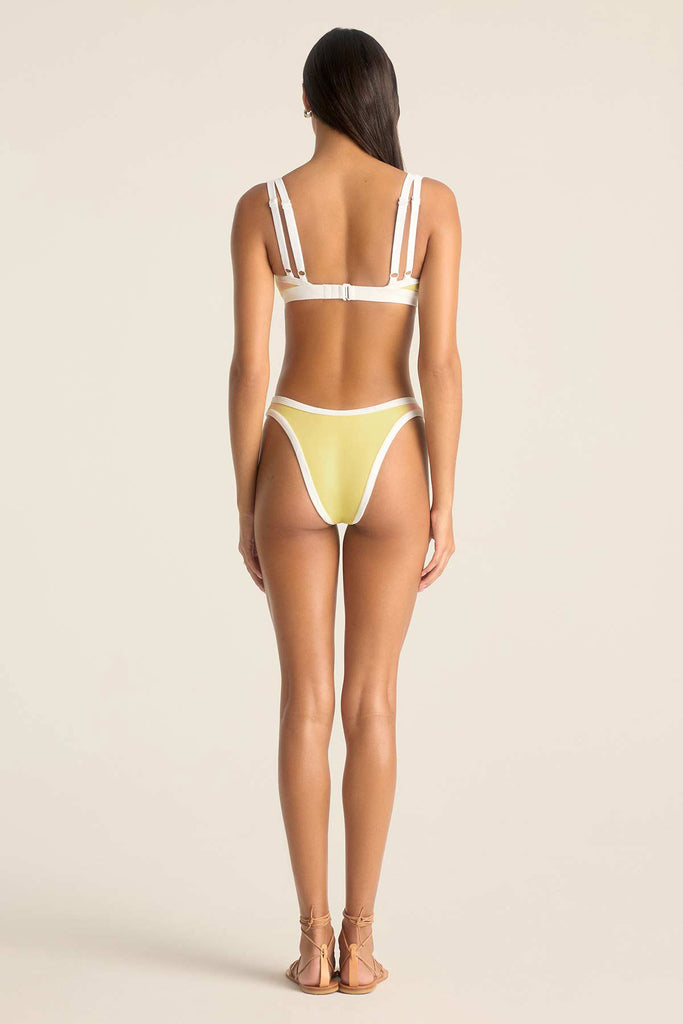 Woman turned away wearing a yellow bikini top with white trim and matching swim bottoms