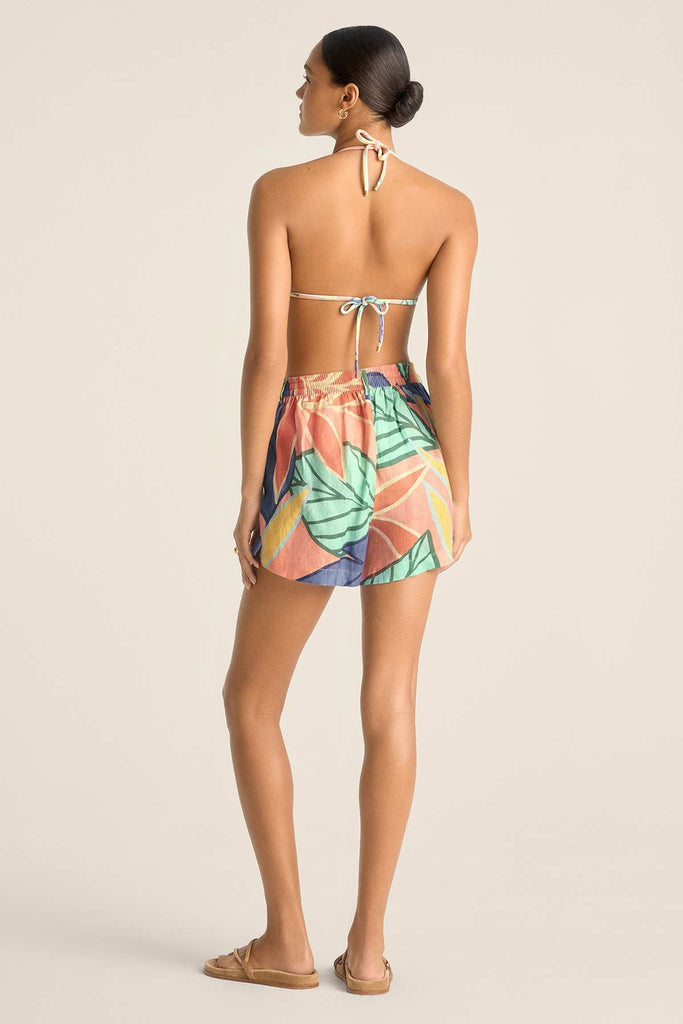 Woman turned away wearing a jungle printed string bikini top and matching beach shorts