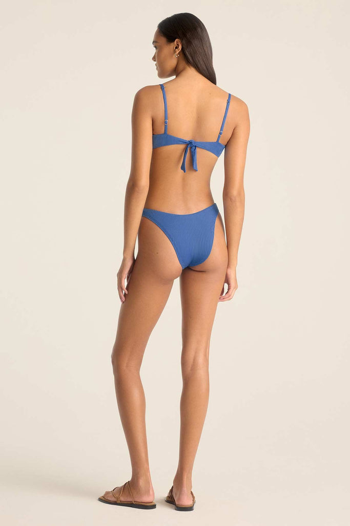 Woman faced away wearing a blue underwire swim top with matching swim bottoms