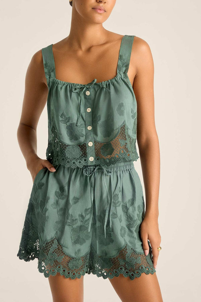 Woman wearing a sea green lacy beach top with matching green beach shorts with a close-up detail on the lace