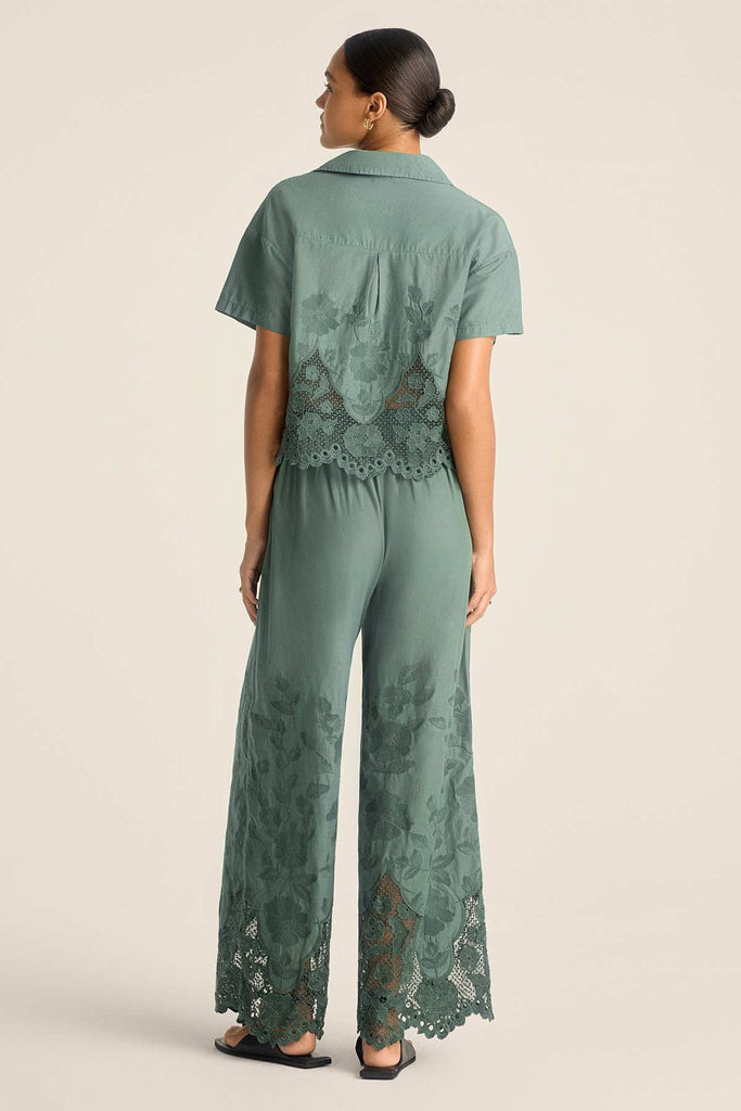 Woman faced away wearing a sea green lacy beach shirt with matching pants 