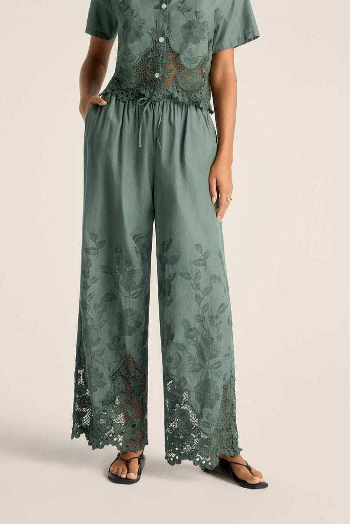 Woman wearing a sea green lacy beach shirt with matching pants with a close-up detail of pants
