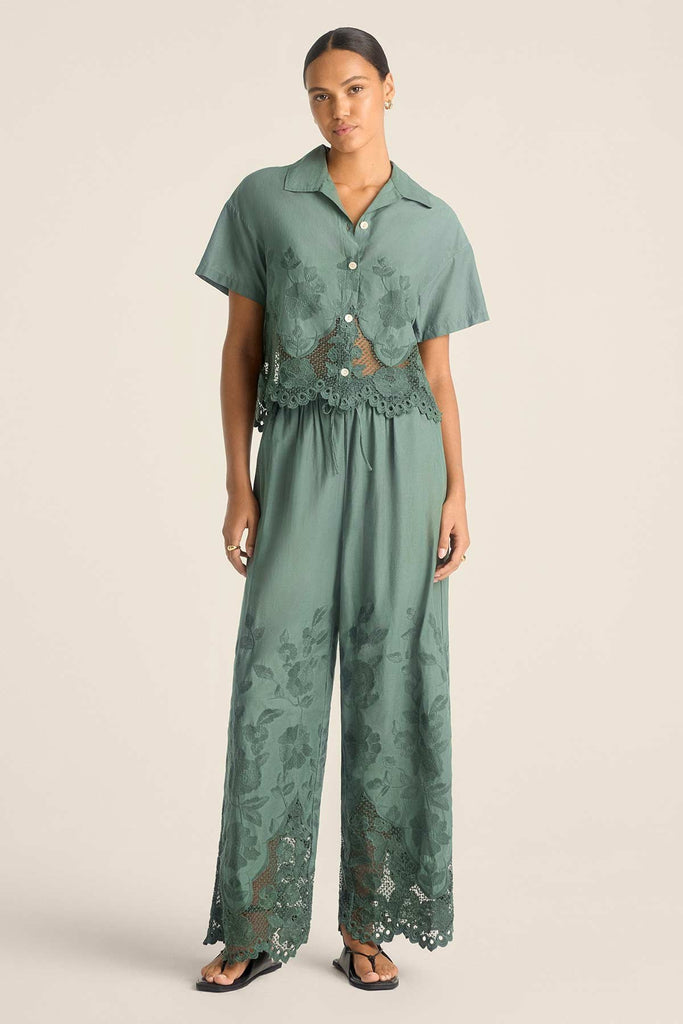 Woman wearing a sea green lacy short sleeve beach shirt with matching pants