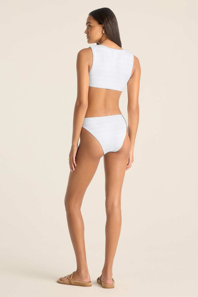 Woman turned away wearing a white swim top and white swim bottoms