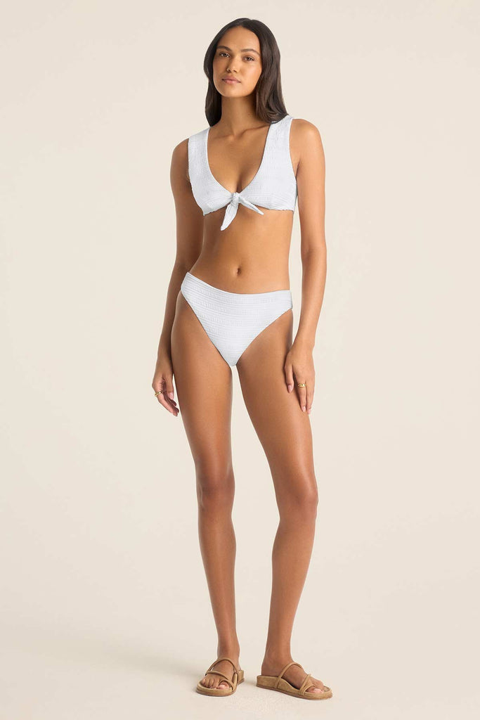 Woman wearing a white swim top with matching white swim bottoms