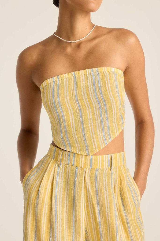 Woman wearing a scarf top with yellow and blue stripes with matching pants detail close up