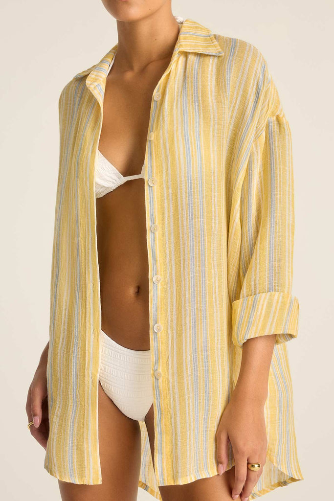 Woman wearing a long sleeve button down beach shirt with yellow and blue stripes