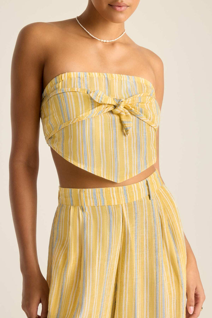 Woman wearing a scarf top with yellow and blue stripes tied in the front with matching pants detail close up