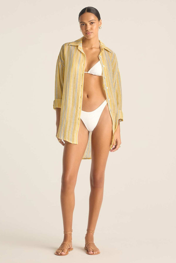 Woman wearing a long sleeve button down beach shirt with yellow and blue stripes