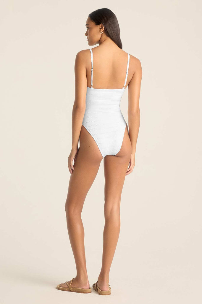 Woman turned away wearing a white one-piece swimsuit with adjustable straps