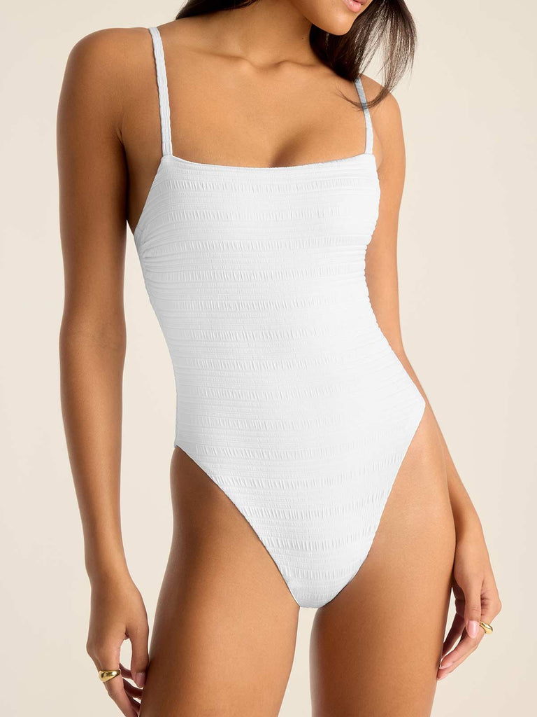 Woman wearing a white one-piece swimsuit with close up on the suit detail 