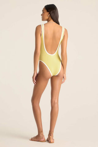 Woman turned away wearing a yellow one-piece swimsuit with white trim