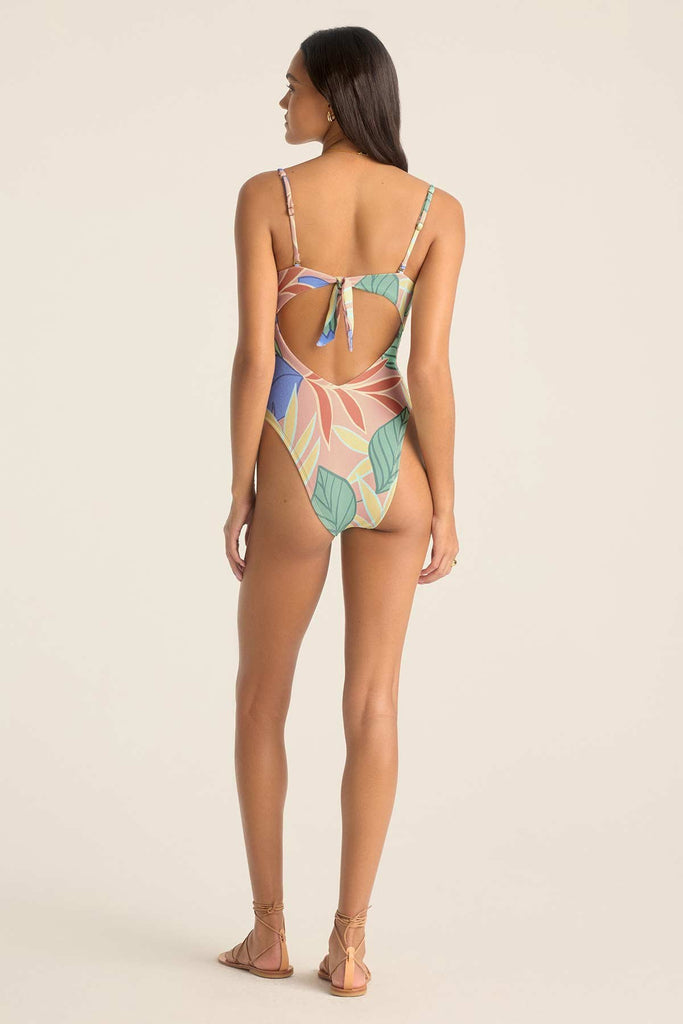 Woman turned away wearing a bandeau one-piece jungle printed swimsuit with straps